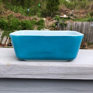 May include: A light blue rectangular baking dish with a white rim. The dish is made of glass and has a vintage look.