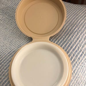 May include: A white ceramic mug with a black handle and the text "But First, Coffee" in a bold, black font. The mug is set against a blurred background, suggesting a cozy setting.