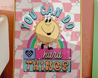 May include: A pink and white checkered background with a gold frame. The text "You Can Do Hard Things" is written in a retro font. A cartoon sun with a rainbow behind it is smiling and holding a heart.