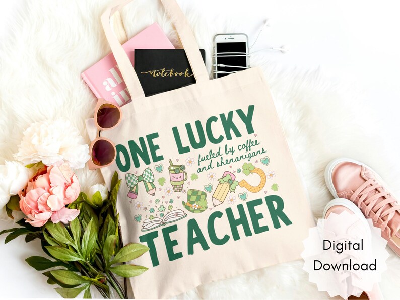 May include: Beige tote bag with the text "ONE LUCKY TEACHER" in green, along with St. Patrick's Day themed graphics. The bag is filled with a pink notebook, a black notebook, a phone, and sunglasses. A pair of pink sneakers is visible.