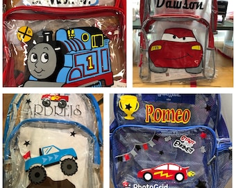 May include: Four clear backpacks with different designs. The first backpack is red with a blue and black train, the second is red with a red car, the third is blue with a monster truck, and the fourth is blue with a red race car. The backpacks have names on them:  'Ryder W.', 'Dawson', 'Ardreis', and 'Romeo'.