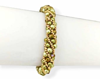 May include: A beaded bracelet featuring a spiral design. The bracelet is primarily olive green with gold-colored beads and accents. The beads are arranged in a pattern, creating a textured appearance. The bracelet is displayed on a white surface.