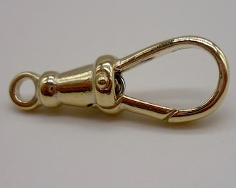 May include: A gold-toned metal clasp with a loop on one end and a hook on the other. The clasp is designed to attach to a chain or strap.