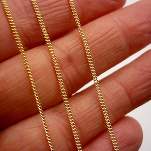 May include: Three gold chains of different lengths, laid out on a hand, showing the different sizes and styles of the chains.