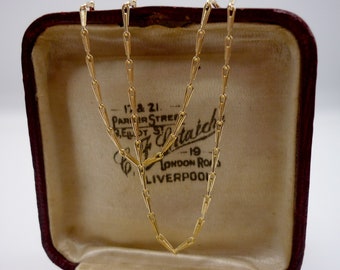 May include: A gold chain necklace in a red velvet jewelry box. The box has a label that reads "17 & 21, Parker Street, Belfast,  H.  Entwistle, 19, London Road, Liverpool."
