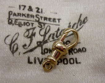 May include: A gold-toned metal clasp with a hook and loop closure. The clasp is on a white fabric background with the text "17 & 21 Parker Street G. Elliot St. C. F. Latch London Road Liverpool" printed on it.