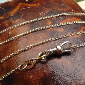 May include: A gold chain with a silver clasp. The chain is made of small, linked circles.