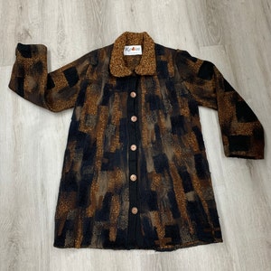May include: A long-sleeved brown and black patterned cardigan with a brown collar and five brown buttons down the front. The cardigan has a label that says "Rain".
