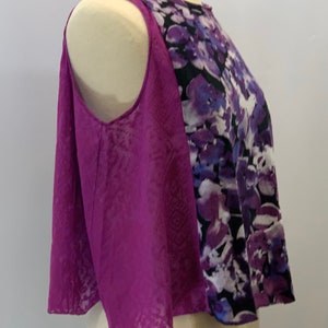 May include: A sleeveless top with a purple and black floral print on one side and a solid purple fabric on the other side. The top has a rounded neckline and a cropped hem.