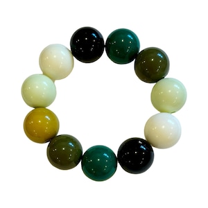 May include: A green, white, and black beaded bracelet with round beads. The beads are arranged in a gradient pattern, starting with white, then light green, then dark green, then black, and then repeating in reverse.