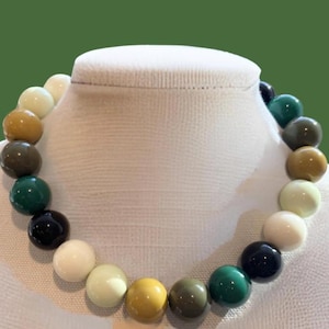 May include: A multi-colored beaded necklace with alternating shades of green, black, white, and yellow.