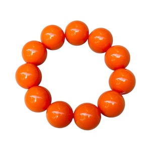 Könnte beinhalten: Ein Armband aus zehn leuchtend orangefarbenen runden Perlen.