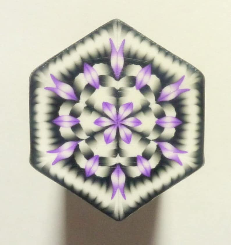 May include: A hexagonal tile with a purple and white mandala design. The mandala features a central flower with eight petals and a repeating pattern of smaller flowers and leaves.