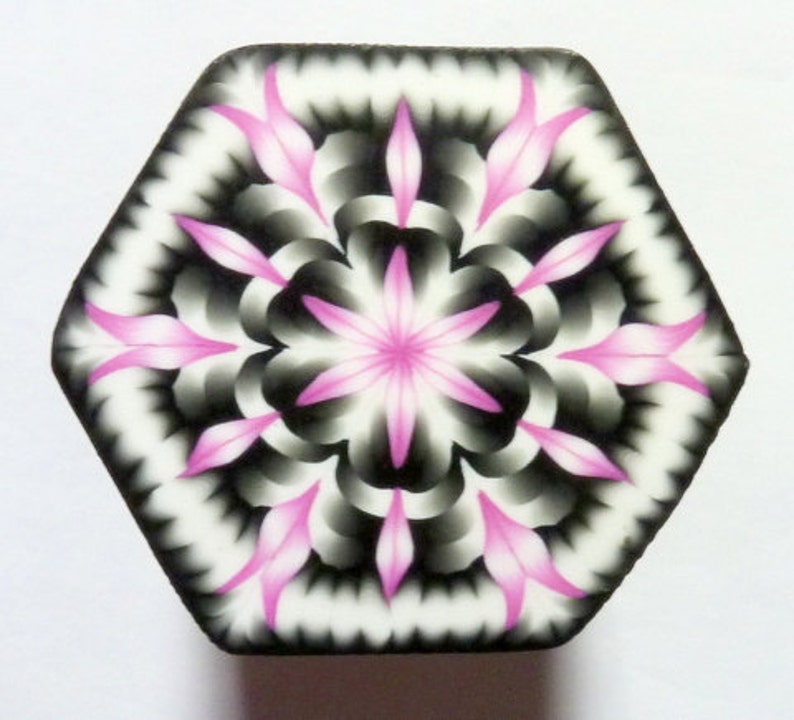 May include: A hexagonal tile with a pink and black geometric pattern. The pattern is symmetrical and features a central star shape.