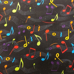 Puede incluir: Una tela negra con un patrón repetitivo de notas musicales de colores y claves de sol. Las notas son de varios colores, incluyendo rojo, amarillo, verde, azul y morado.