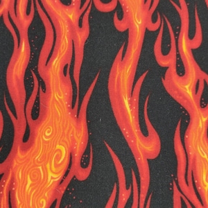 Op de afbeelding: Een zwarte stof met een herhalend patroon van oranje en rode vlammen. De vlammen zijn gestileerd en hebben een textuur.
