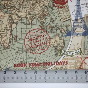May include: Fabric with a vintage world map design. The map features continents, oceans, and travel-themed elements like compasses, stamps, and the Eiffel Tower. Text includes "Around the World" and "Book Your Holidays". The fabric is measured with a ruler.