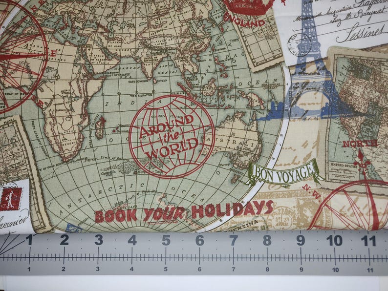 May include: Fabric with a vintage world map design. The map features continents, oceans, and travel-themed elements like compasses, stamps, and the Eiffel Tower. Text includes "Around the World" and "Book Your Holidays". The fabric is measured with a ruler.
