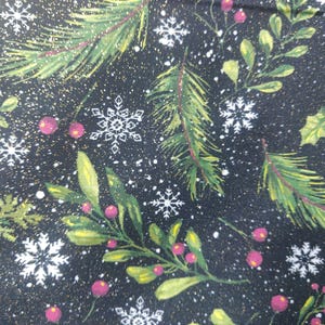 May include: A black fabric featuring a festive pattern of green pine branches, holly leaves, and red berries interspersed with white snowflakes and small gold specks. The design creates a dense, repeating winter-themed botanical print.