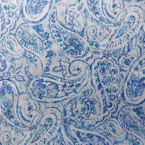 Pode incluir: Um tecido branco com um padrão paisley azul. O padrão paisley é um design tradicional indiano que é frequentemente usado em têxteis e roupas.