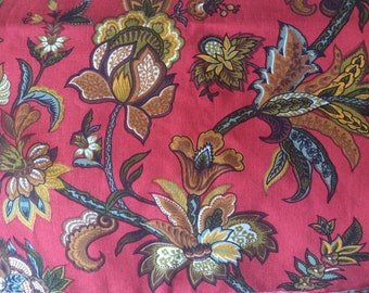 May include: Red fabric with a floral pattern featuring brown, green, and yellow flowers. The fabric has a paisley design.