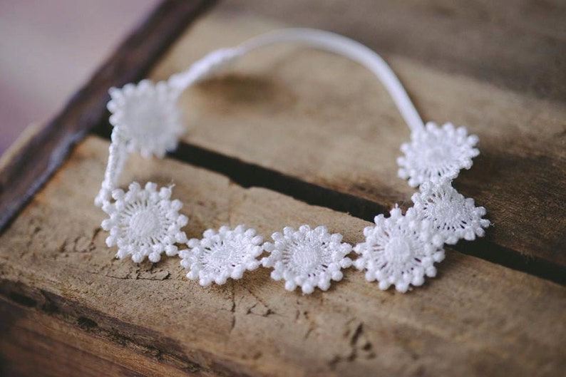 May include: White lace headband with a delicate floral design. The headband is made of a soft, flexible material and is perfect for adding a touch of elegance to any outfit.