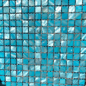 May include: A sheet of blue iridescent mosaic tiles, each tile is square shaped and arranged in a grid pattern. The tiles are set in a mesh backing.
