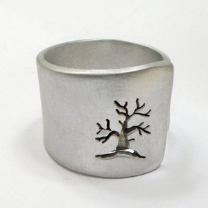 Open aluminum band ring with perforated tree perpendicular to the ring, and custom text.
