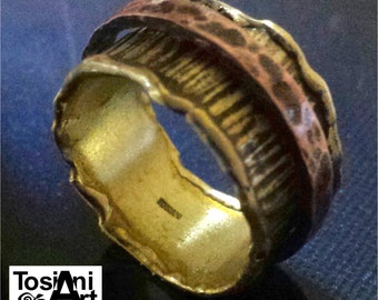 May include: A gold ring with a textured, hammered finish. The ring is made of two bands, one wider than the other, and has a slightly irregular shape.