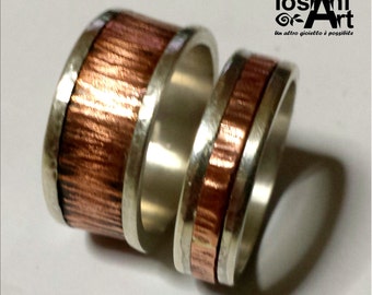 A pair of engagement rings, silver with center of copper and custom text.