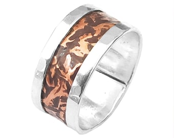 May include: A silver band ring with a copper inlay. The copper inlay has a hammered texture and a brown and orange color.