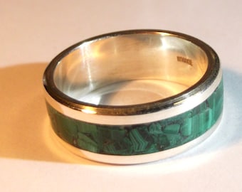 May include: A silver ring with a green malachite inlay. The ring has a polished silver band and a green stone inlay.