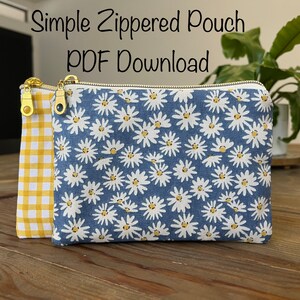 May include: A blue zippered pouch with a white daisy print and a yellow gingham lining. The pouch has gold zippers and is sitting on a wooden surface. Simple Zippered Pouch PDF Download.