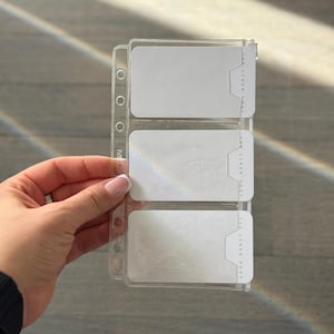 A hand is holding a clear plastic organizer with three compartments, each containing a white label.