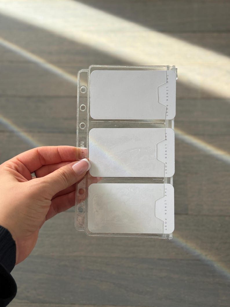 A hand is holding a clear plastic organizer with three compartments, each containing a white label.