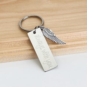 May include: Silver keyring with a small angel wing charm and a rectangular tag that reads "Always with you."