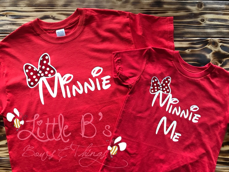 Puede incluir: Dos camisetas rojas con texto blanco y un lazo rojo y blanco de lunares. La camiseta m&aacute;s grande dice "Minnie" y la camiseta m&aacute;s peque&ntilde;a dice "Minnie Me".