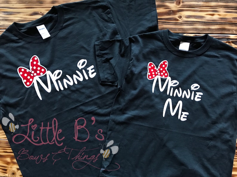 Puede incluir: Dos camisetas negras con texto blanco y un lazo rojo con lunares blancos. La camiseta m&aacute;s grande dice "Minnie" y la m&aacute;s peque&ntilde;a dice "Minnie Me".