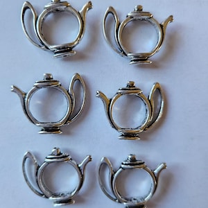 May include: Six silver teapot charms with a detailed design. The charms are hollow and have a ring on the top for attaching to a bracelet or necklace.