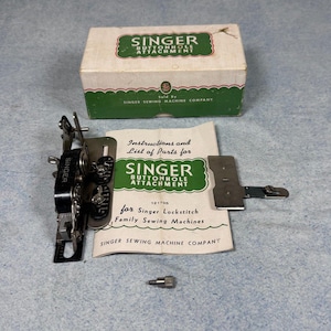 May include: A vintage Singer buttonhole attachment set including a black and silver metal mechanism, a small metal screw, and an instruction manual. The items are presented with a white and green cardboard box labeled Singer Buttonhole Attachment.