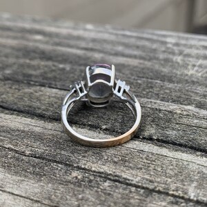 以下が含まれることがあります： 大きな楕円形の紫色の宝石と2つの小さなアクセントストーンが付いたシルバーリング