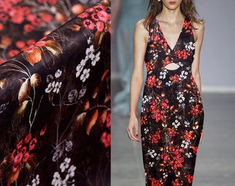 May include: A black dress with a floral print featuring red and white flowers. The dress has a V-neckline and a cut-out detail at the waist.