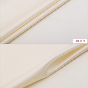 May include: Close-up of a smooth, off-white fabric with a subtle sheen. The fabric is folded in half, creating a soft curve. The text "3号 乳白" is visible in the bottom right corner of the image.