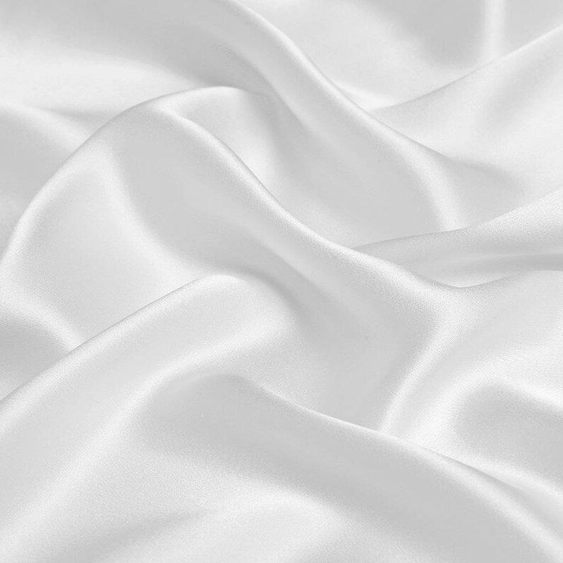 May include: White satin fabric with soft, flowing folds and a smooth, luxurious texture.