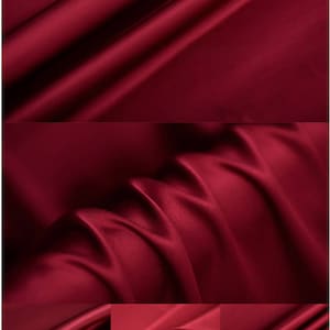 May include: Close-up of a deep red satin fabric with a smooth, silky texture. The fabric is folded and draped, showcasing its luxurious drape and sheen.