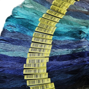May include: A collection of 18 skeins of embroidery floss in shades of blue and teal. The floss is wound around yellow cardboard spools with barcodes and numbers printed on them. The numbers on the spools are 823, 311, 336, 796, 797, 19, 51, 799, 798, 322, 99, 384, 3846, 3766, 597, 20, 5, 3755, 318932, and 794.