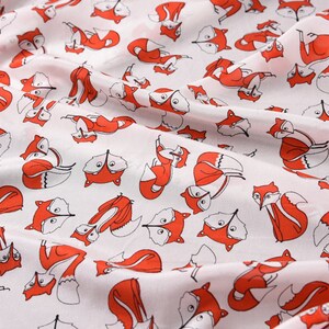 May include: White fabric with a repeating pattern of red foxes. The foxes are drawn in a simple, cartoon style and are facing different directions.