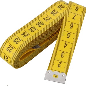 May include: A yellow measuring tape with black markings and numbers. The tape is rolled up and the end is secured with a silver metal clip.