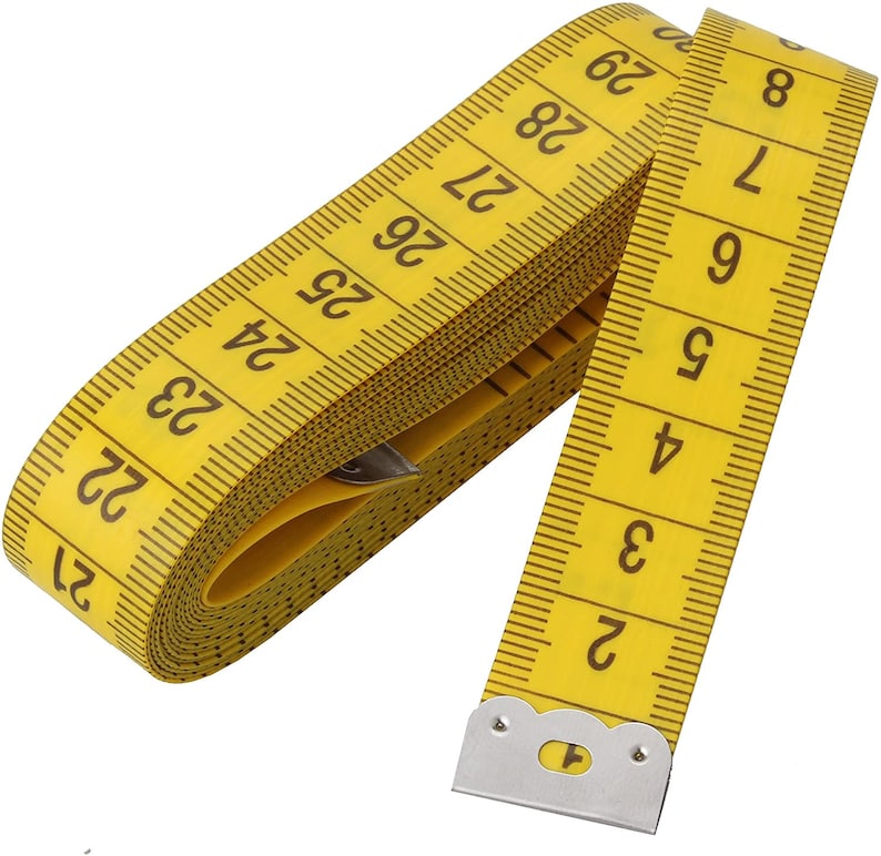 May include: A yellow measuring tape with black markings and numbers. The tape is rolled up and the end is secured with a silver metal clip.