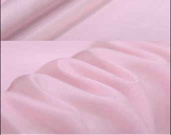 May include: Close-up of a pale pink fabric with a smooth, silky texture. The fabric is folded and draped, showcasing its drape and flow. The fabric is light and airy, perfect for creating garments or home decor.